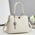 Close-up of beige lychee grain leather handbag with vintage buckle and floral pendant - Off White