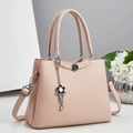 Close-up of the light pink leather handbag showing texture and metal flower pendant detail - Pink