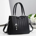 Détail du sac à main noir avec texture grainée et pendentif floral argenté - Noir