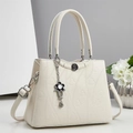 Dettaglio borsa beige con motivi a cuore goffrati e ciondoli a forma di fiore - Bianco Sporco