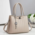 Détail du sac à main beige montrant la texture alvéolée et le pendentif floral - Abricot