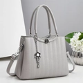 Detail of light gray crossbody bag with honeycomb texture and floral chain pendant - Gray