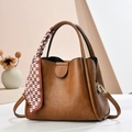 Classic caramel leather bucket bag with top handles, crossbody strap and silk scarf detail - Earthy Yellow