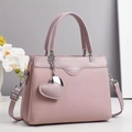 Gros plan du sac à main rose clair texture litchi avec pendentif cœur et logo gaufré - Violet