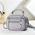 Detail of lavender litchi leather bag showing multi-zipper layers and silver hardware - Light Purple