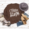 Vue à plat du sweat Coffee & Books marron avec accessoires sur fond bois blanc - S / Sweat-shirt Café (Police Blanche)