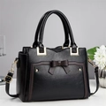 Detail of black lychee leather handbag with bow decor, gold hardware and metal bottom studs - Black