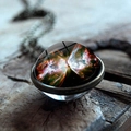Macro detail of the bronze galaxy nebula glass ball pendant on a rustic wood surface - Butterfly Nebula Style (JY001624-2)