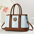 Dettaglio della borsa tote in tela a righe blu con manici in pelle marrone e logo G - Blu