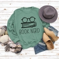 Flat lay of green Book Nerd sweatshirt with glasses print and autumn style accessories - S / Light Green (Black Text)