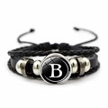 Dettaglio del bracciale in pelle intrecciata con cupola in vetro nero e lettera B - Lettera B