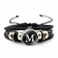 Detailed macro view of multilayer leather bracelet with a glass dome M letter charm - Letter M