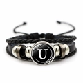 Detail of a braided leather multi-layer bracelet featuring a white letter U glass dome - Letter U