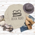 Beiges Book Nerd Sweatshirt mit Brillenprint auf weißem Holzhintergrund liegend - S / Sandfarben (Schwarze Schrift)