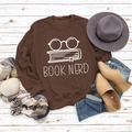 Flat lay of brown Book Nerd sweatshirt styled with autumn accessories on white wood - S / Coffee (White Font)