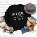 Flachbild-Layout von schwarzem Langarm-Sweatshirt mit 'FREE HUGS' Spruch und Herbstdeko - S / Schwarzes Sweatshirt (Weiße Schrift)