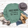 Flat lay of green long sleeve sweatshirt with Free Hugs slogan and chic accessories - Light Green Sweatshirt (Black Font)