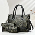Detailed close-up of glossy black embossed tote bag with gold floral patterns and handles - Gold