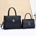 Detail of black pebbled leather handbag set with striped pleats and blue enamel clasp - Blue