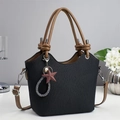Close-up of black pleated tote bag featuring brown ring handles and star charm detail - Black