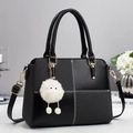 Detail of black crossbody bag featuring contrast stitching, gold buckle, and plush charm - Black