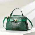 Close-up of dark green crocodile embossed handbag with a gold CD metal clasp - Green