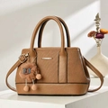 Brown textured leather handbag with plush charm on a minimalist display stand - Brown