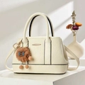 Detail of cream white textured leather handbag with plush charm on a geometric stand - Off White