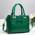 Close-up of vibrant green faux crocodile leather bag featuring a bow and gold hardware - Green