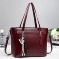 Detail of burgundy PU leather tote bag with decorative charms and twin top handles - Burgundy