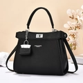 Borsa tote nera bicolore con finiture argentate e tracolla su una scrivania neutra - Medio / Nero
