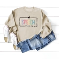 Detailaufnahme khakifarbenes Sweatshirt mit Speech Therapy Aufdruck auf Holzgrund - S / Sandfarben (Schwarze Buchstaben)
