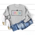 Flat lay of gray long-sleeve sweatshirt with colorful Speech Therapy print on wood - Grey (Black Print)