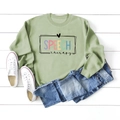 Flat lay of green Speech Therapy sweatshirt with denim shorts and white sneakers - Olive Green (Black Letters)