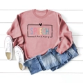 Detail of pink Speech Therapy sweatshirt with letter print on white wood floor - Rose Gold (Black Letters)