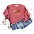 Close-up of Books and Coffee print on a brick red sweatshirt styled with blue jeans - S / Red