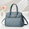 Détail d'un sac à main en cuir bleu-gris avec fermoir doré et texture grainée - Bleu