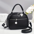 Detail of black lychee grain leather crossbody bag with heart pendant and silver hardware - Black