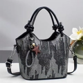 Minimalistische bucket bag met zilveren lovertjes en een geknoopte hendel op wit bureau - Zwart