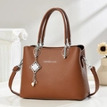 Sac à main élégant en cuir marron grainé avec pendentif argenté sur fond minimaliste - Jaune Terre