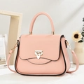 Gros plan d'un sac à main rose en cuir grainé avec fermoir doré et poignée ronde - Rose