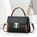 Elegante bolso de cuero granulado negro y marrón con cierre en T dorado en exhibición - Negro