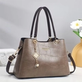 Close-up of brown crocodile texture leather handbag with gold metal logo and tassel charm - Gray