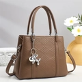 Detail der braunen Ledertasche mit Karostruktur und silbernem Ballon-Hund-Anhänger - Braun