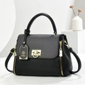 Dettaglio della borsa in pelle nera con hardware dorato e ciondolo in metallo logo - Nero