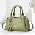 Grass green pebble leather handbag with dual handles and star charm shown in a minimalist studio - Green