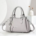 Detail of light gray lychee grain leather handbag with silver star chain charm accessory - Gray