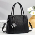 Detail of black quilted tote bag with silver balloon dog charm and leather texture - Black