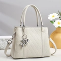 Close-up of quilted cream tote bag with silver balloon dog charm and leather handle - Off White