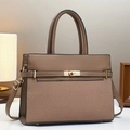 Close-up of brown textured leather handbag with gold twist lock and protective metal feet - Brown